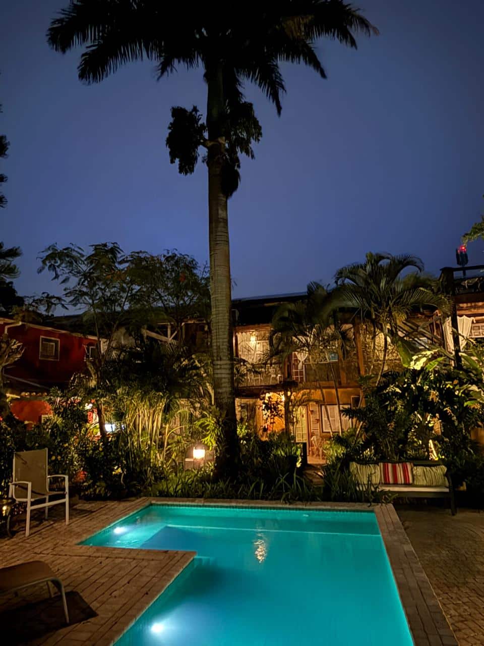Piscina e jardim da Takahouse iluminados ao entardecer